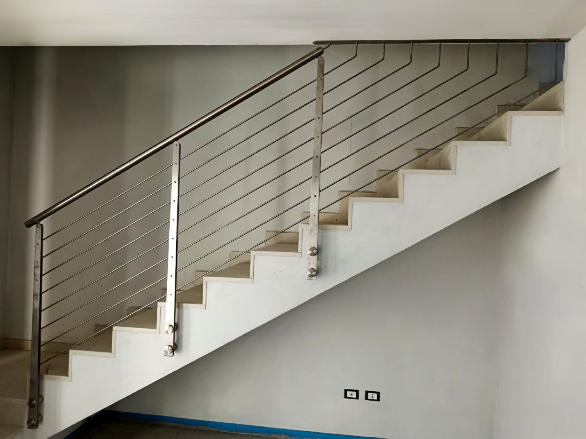 Ringhiera interna in acciaio inox satinato con tondini orizzontali trattenuti dai montanti in doppio piatto con piastre di ancoraggio a parete.